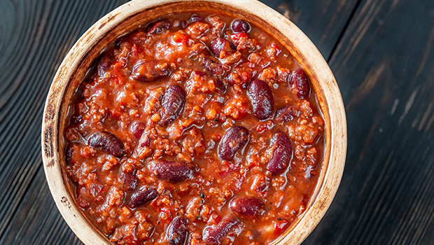 This is an image of a wooden bowl filled with bean chili.