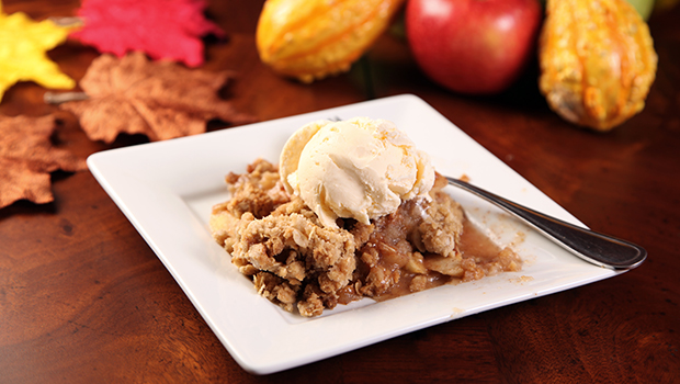Baked apple and crumb topping with a scoop of vanilla ice cream melting on top.