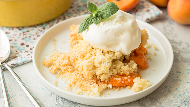 Scoop of apricot cobbler with ice cream on top all on a white plate