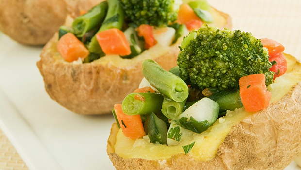 Two baked potatoes stuffed with chopped green beans, broccoli, and chopped carrots