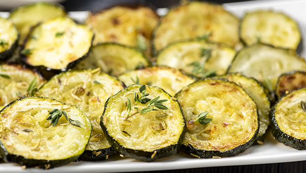 Eighteen baked zucchini rounds on a white plate