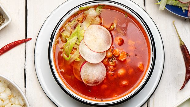 Top-down view of pozole soup with radishes and cabbage garnish