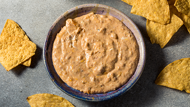 Bean dip in a ceramic bowl surrounded by tortilla chips