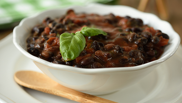 Black bean soup in a white bowl with a wooden spoon