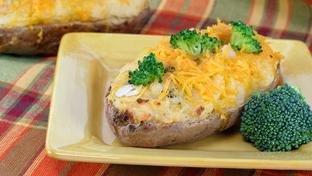 Baked potato with broccoli and shredded cheese, all on a square yellow plate