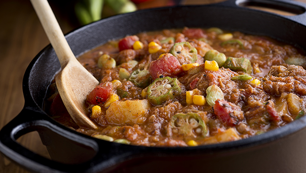 Brunswick stew in a large black pot with a wooden spoon