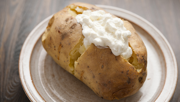 Baked potato with dollop of cottage cheese, on a ceramic plate