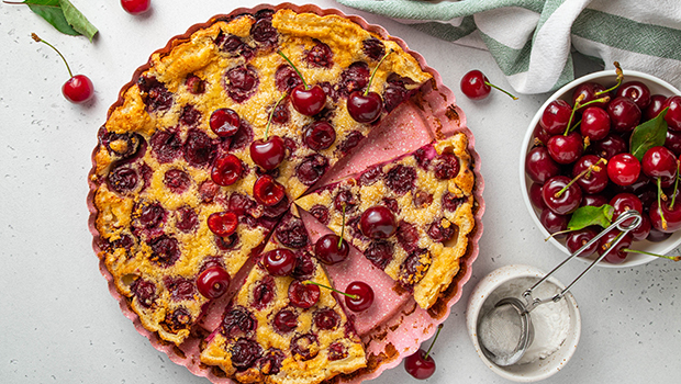 Top down view of cherry clafoutis with two slices and small bowl of cherries