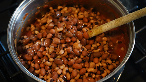 Cooked kidney beans in a silver pot with a wooden spoon