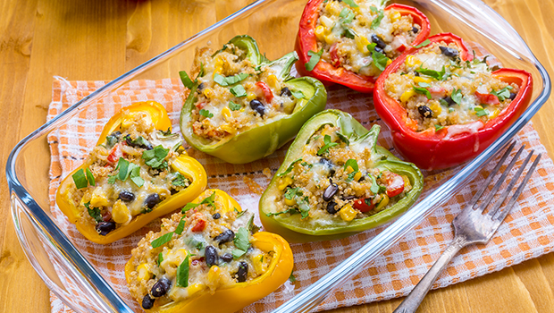 Red, green, and yellow stuffed peppers in a clear pyrex dish