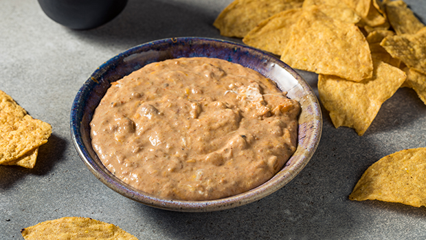 Mashed bean dip in a ceramic bowl with tortilla chips