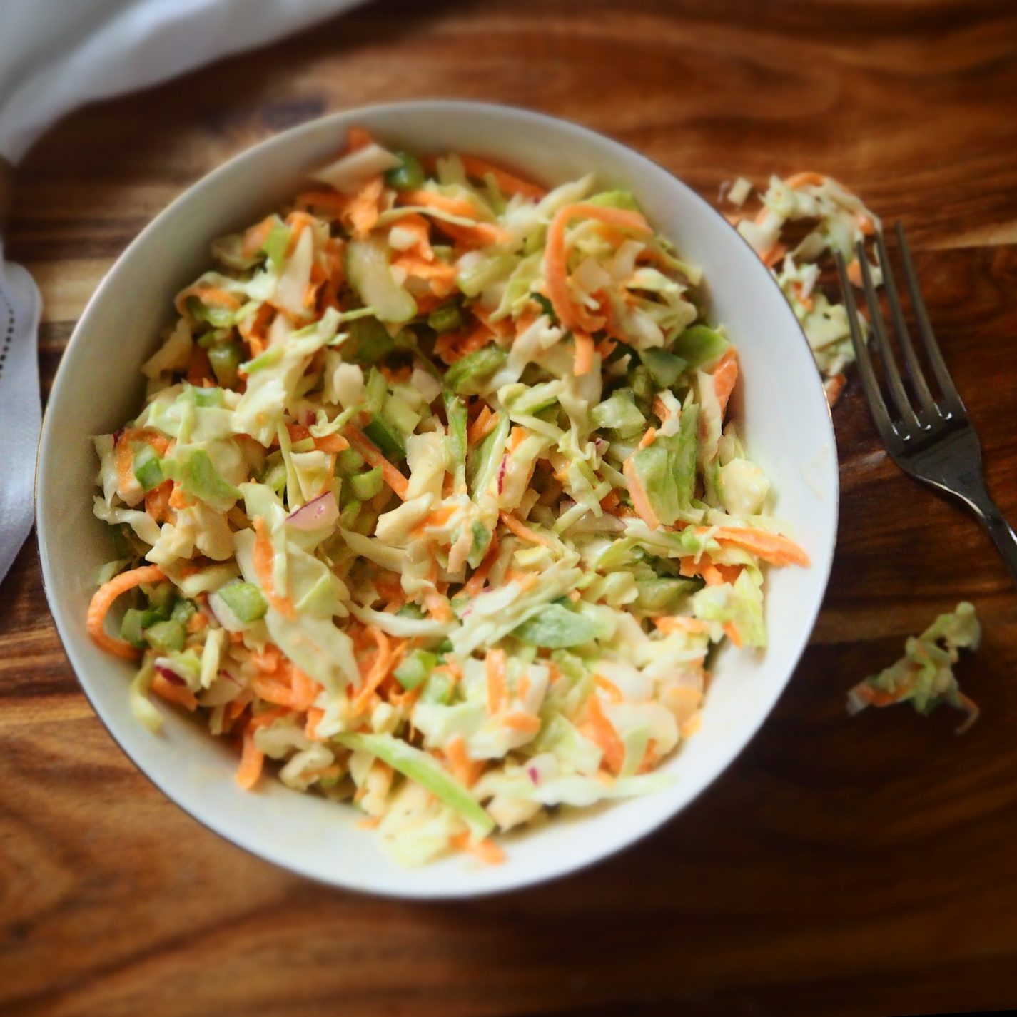 Top-down view of a white bowl containing cole slaw with zucchini