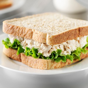 Diced apple and tuna with mayonnaise sauce and a slice of lettuce in between two slices of white bread