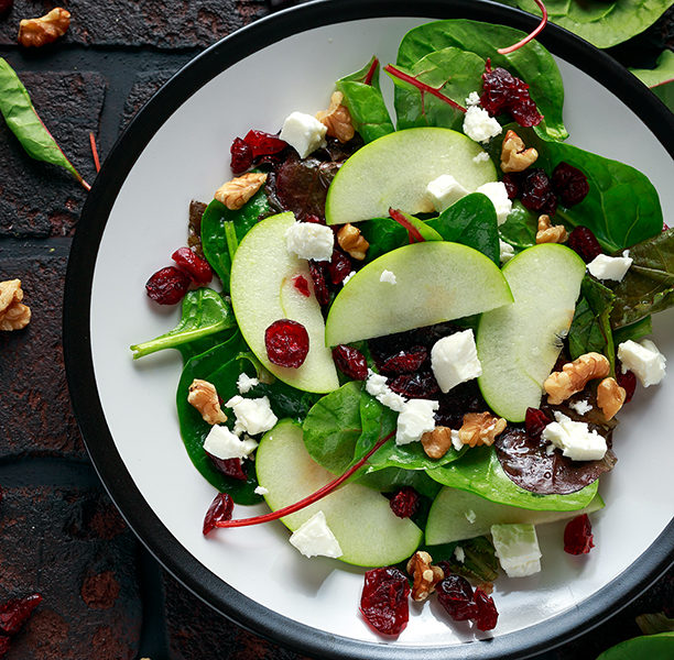 Sliced green apples with spinach, dried cranberries, crumbled goat cheese, and walnuts with a dressing glaze.